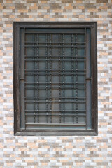 Window with mesh and bars on a tiled wall.