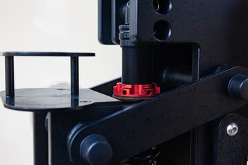 A steel mechanism with a threaded stem and a red clamping nut on it.
