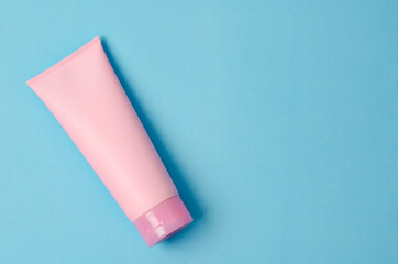 Empty a cosmetic pink tube of cream on blue background