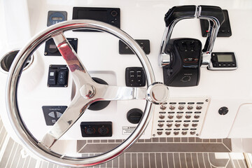 Luxury yacht control panel with steering wheel, gear levers, navigation devices and control buttons.