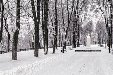 Winter park with trees, cameoes and pavement covered with snow after a snowfall.
