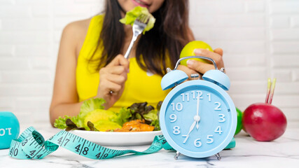Selective focus with blue alarm clock which ready eating a healthy food -Intermittent fasting concept