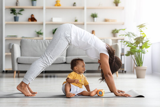 Young black mother practicing yoga at home with her infant son