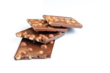 A few pieces of milk chocolate with hazelnuts on a white background