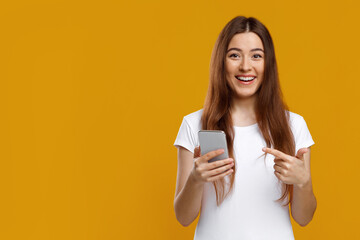 Emotional young woman pointing at new smartphone in her hand