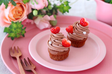 Chocolate cupcakes with chocolate cream with strawberry heart. 
Valentine bouquet of rose flowers  and gift.
