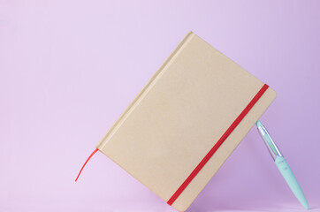 Recycled paper agenda with pen on pink background