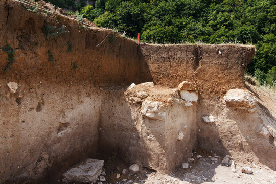 Archaeologists dug a hole on hillside to search for historical artifacts. Archaeological work