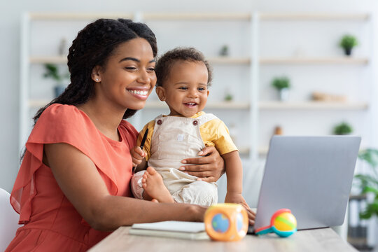 Black Mom Working On Laptop And Taking Care About Baby At Home