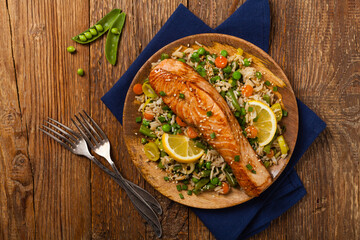 Asian dish. Fried salmon with rice and vegetables. Sprinkled with sesame seeds.