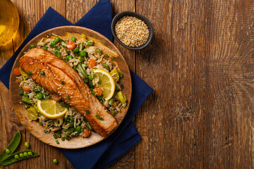 Asian dish. Fried salmon with rice and vegetables. Sprinkled with sesame seeds.