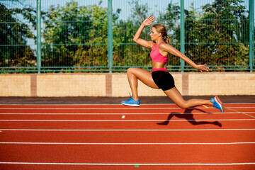 Fototapeta na wymiar Side view beautiful young woman exercise jogging and running on athletic track on stadium