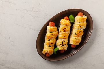 Sausage baked in puff pastry. Sprinkled with sesame seeds, served with sauce.