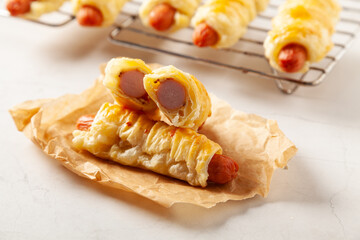 Sausage baked in puff pastry. Sprinkled with sesame seeds, served with sauce.