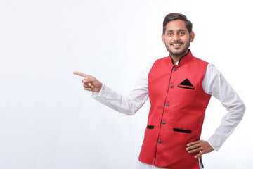 young indian man in traditional wear and showing direction on white background.