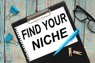 Find Your Niche. text on white notepad paper on black folder on wood background