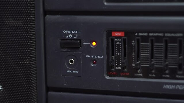Power button on a cassette recorder. Dark body. Old tape recorder. Red LED. Close-up. Man's hand.