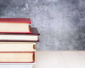 a stack of books on a table against a concrete wall