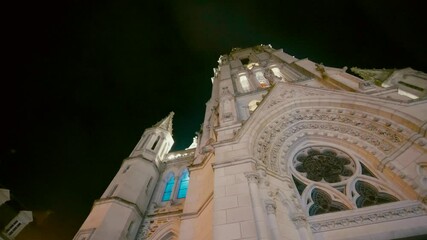 Beautiful steadicam shot in extreme low angle of ancient church in France, the camera turn around it. Shot during Christmas illuminated at night. Some blue light get out of the stained glass.