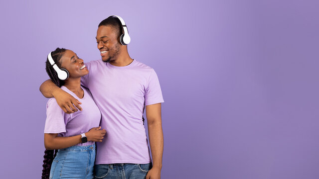 Portrait of black couple in headphones hugging at studio, banner
