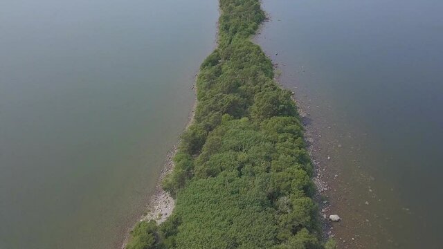 Drone shot tilt up revealing narrow island.