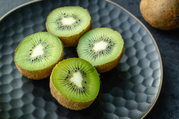 Fresh juicy kiwi fruit on a plate. Dark background