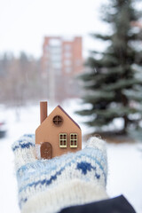 A model of an eco-friendly wooden house in the hands on a winter background.