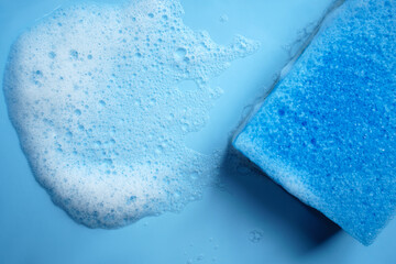 Cleaning blue sponge and a soapy foam on a background. Cleaning concept, cleaning service. Banner. Flat lay, top view