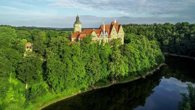Czocha medieval castle in Lower Silesia in Poland. Built in 13th century  with many later additions. Aerial 4K approaching video in summer, early morning. Water reflection in Kwisa river and forests 