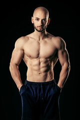 Fototapeta na wymiar Athletic man with hands in pocket look straight at camera while show his well trained abs