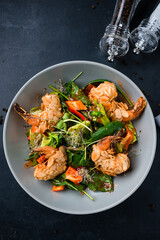 Shrimp salad with fresh green arugula leaves and avocado, almond and sesame seeds