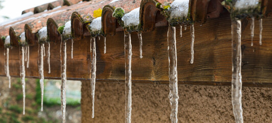 Bannière de glaçons d'eau qui coule figée en stalactites sur un toit de tuiles