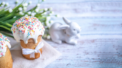Easter cake, with a porcelain rabbit in the background, on a white table. Selective focus. Copy the place for the text.
