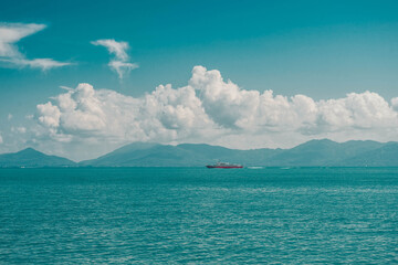 Beautifu turquoise landscape with mountains and sea view and red ship in the distance. Thailand.