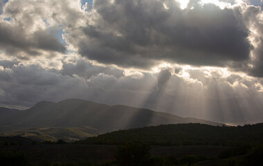 Beautiful rays of light from behind the clouds in the valley above the hills