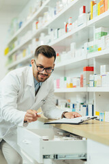 Naklejka na ściany i meble Portrait of a handsome pharmacist working in a pharmacy