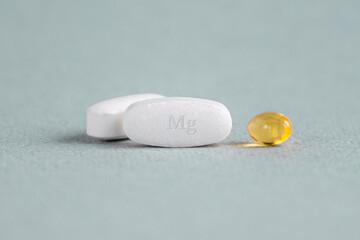 A complex of Mg ( magnesia, magnesium ) and vitamin D ( omega 3 ) capsules for treatment and human health on a light background. Copy space.