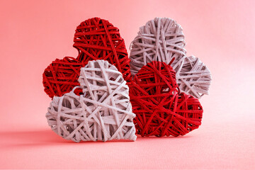 Heart-shaped figures in white and red on a pink background. Wicker figures.