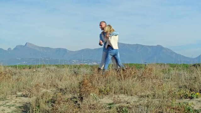 Happy man carrying mature woman in nature