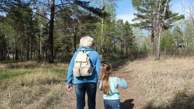Grandmother walking along path with granddaughter.  walking relaxing outdoors in the park or forest