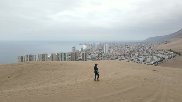 Aerial shot of a tourist taking video for reaching the top of the famous Cerra Dragon Dune at Tarapaca, Iquique Chile Latin America.
