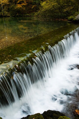 Soft water pouring over threshold on the river in the woods