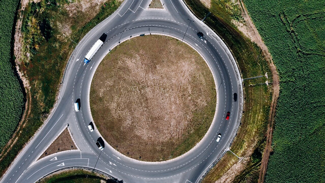 Roundabout traffic of cars and trucks on the circle ring road aerial top view