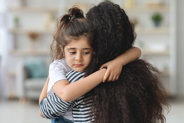 Upset little girl hugging her mom, closeup portrait