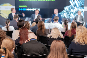 Company of businesspeople listening to presentation at conference