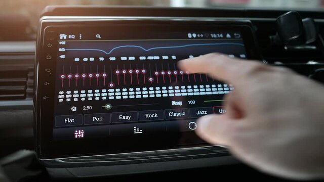Man finger changing car audio equalizer settings using smart multimedia, modern touch screen audio stereo system, transportation and vehicle concept, close up with selective focus