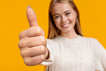 Cute teen girl showing big thumb up on yellow