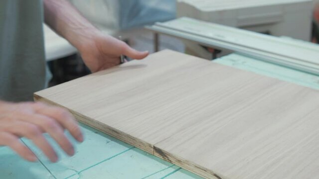 Carpenter marking sheet of oak veneer plywood. Medium Shot