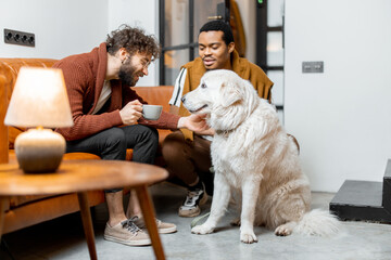 Men care their huge white dog at cozy home. Concept of homosexual relations and lifestyle at home....