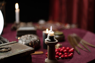 A dark photo of candles, lamps and beads on a fortune teller's table. Interior concept